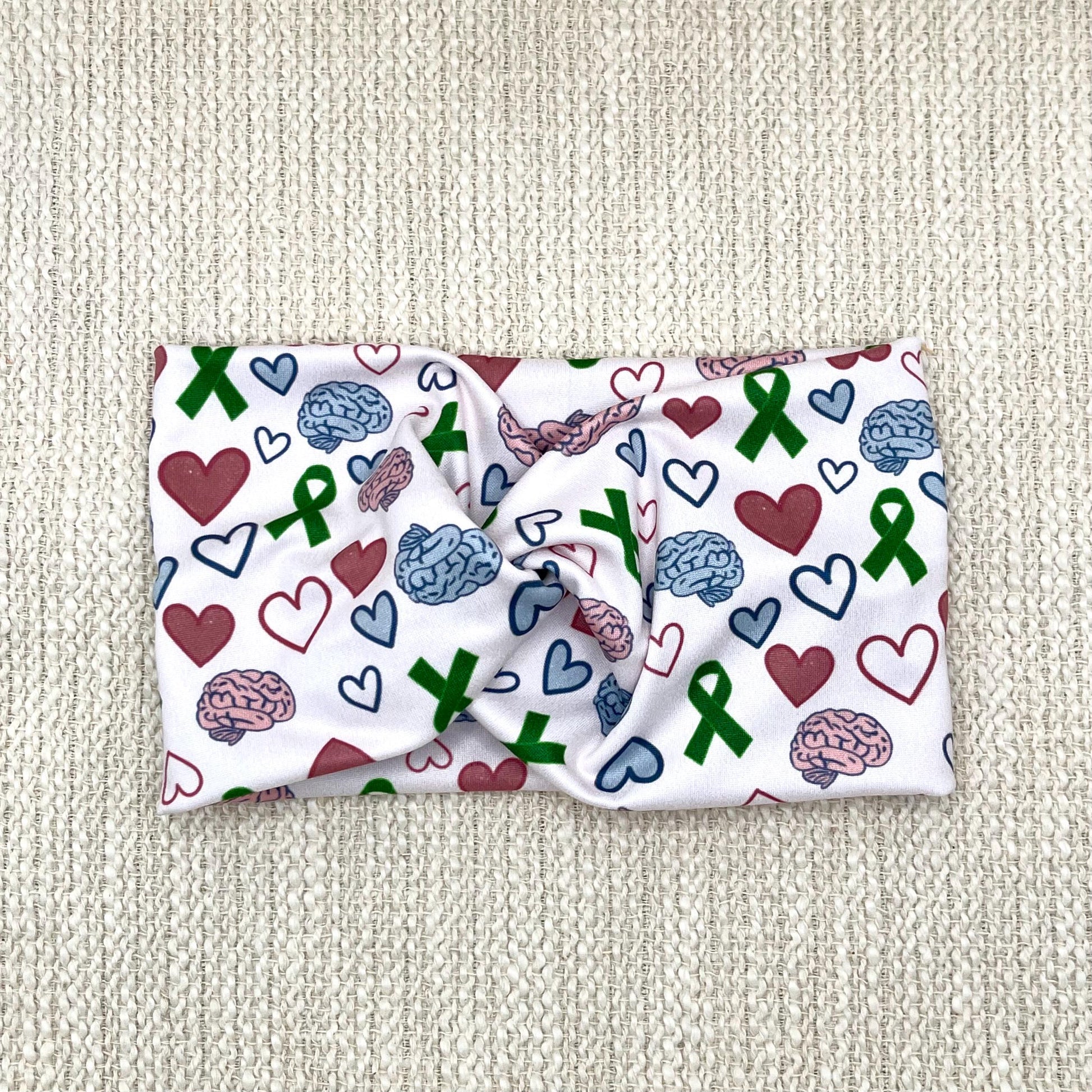 Wide, twisted headband with green ribbon, pink and blue brain, and pink and blue heart print.