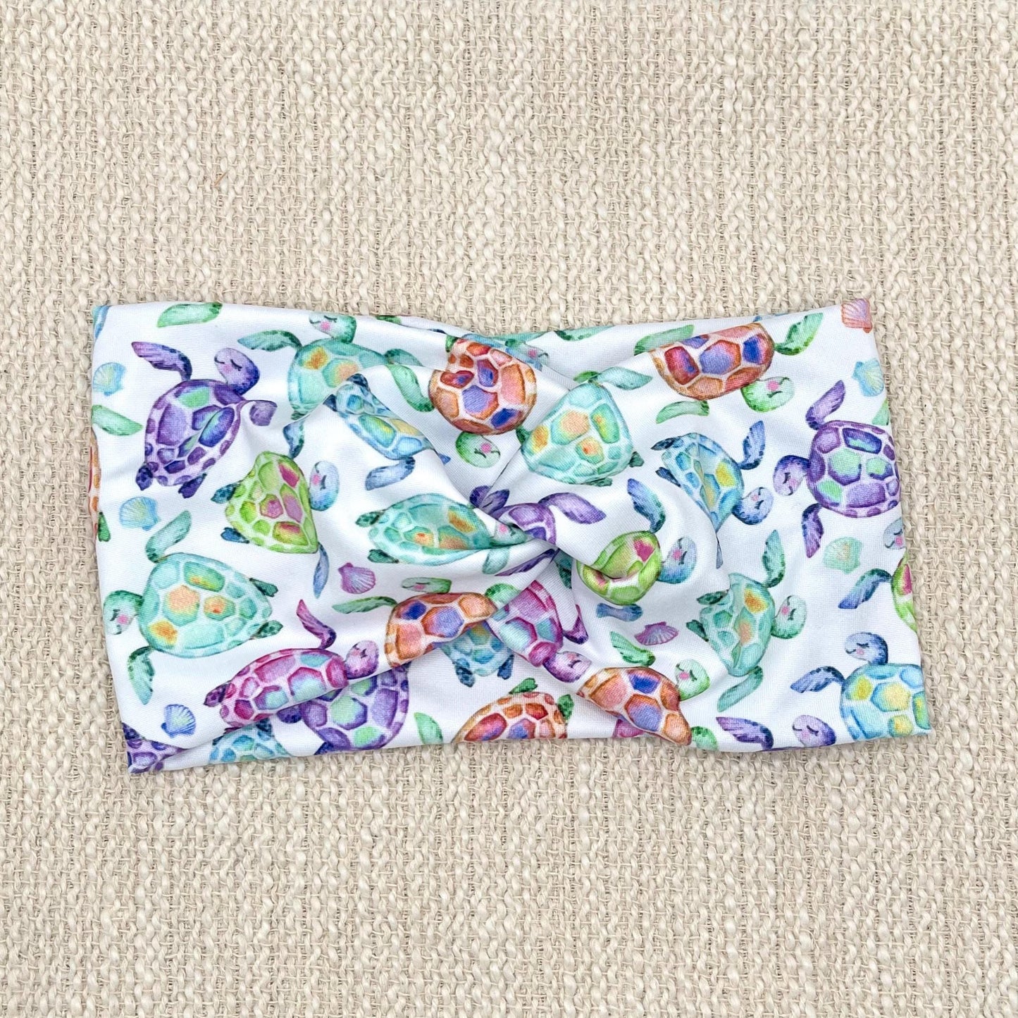 Wide, twisted, white headband with sea turtle print.