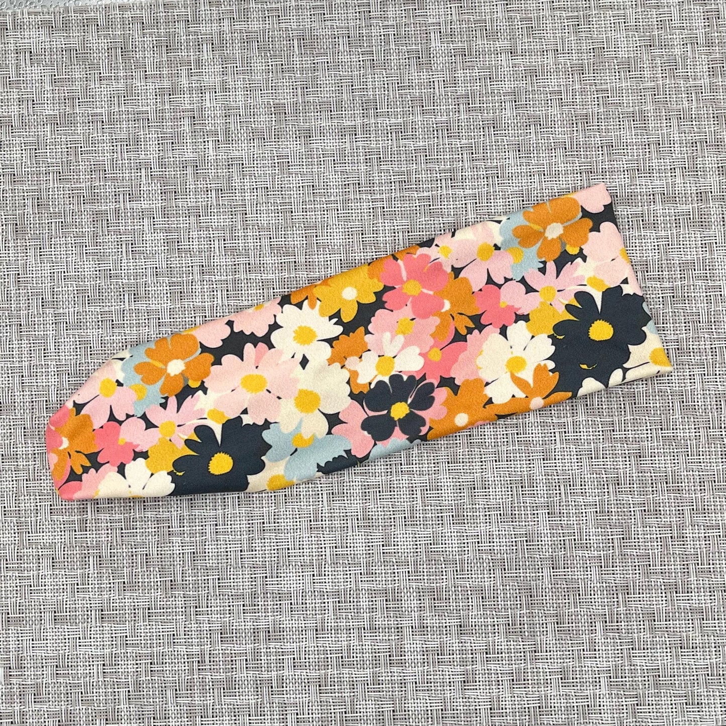 Headband with light and dark pink, navy, light blue, white, yellow, and orange flower print.
