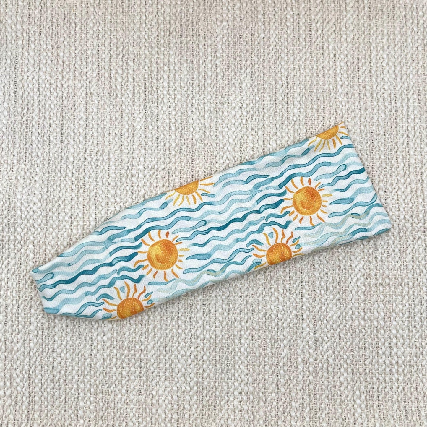 Flat, stretchy headband with blue waves and sun print.