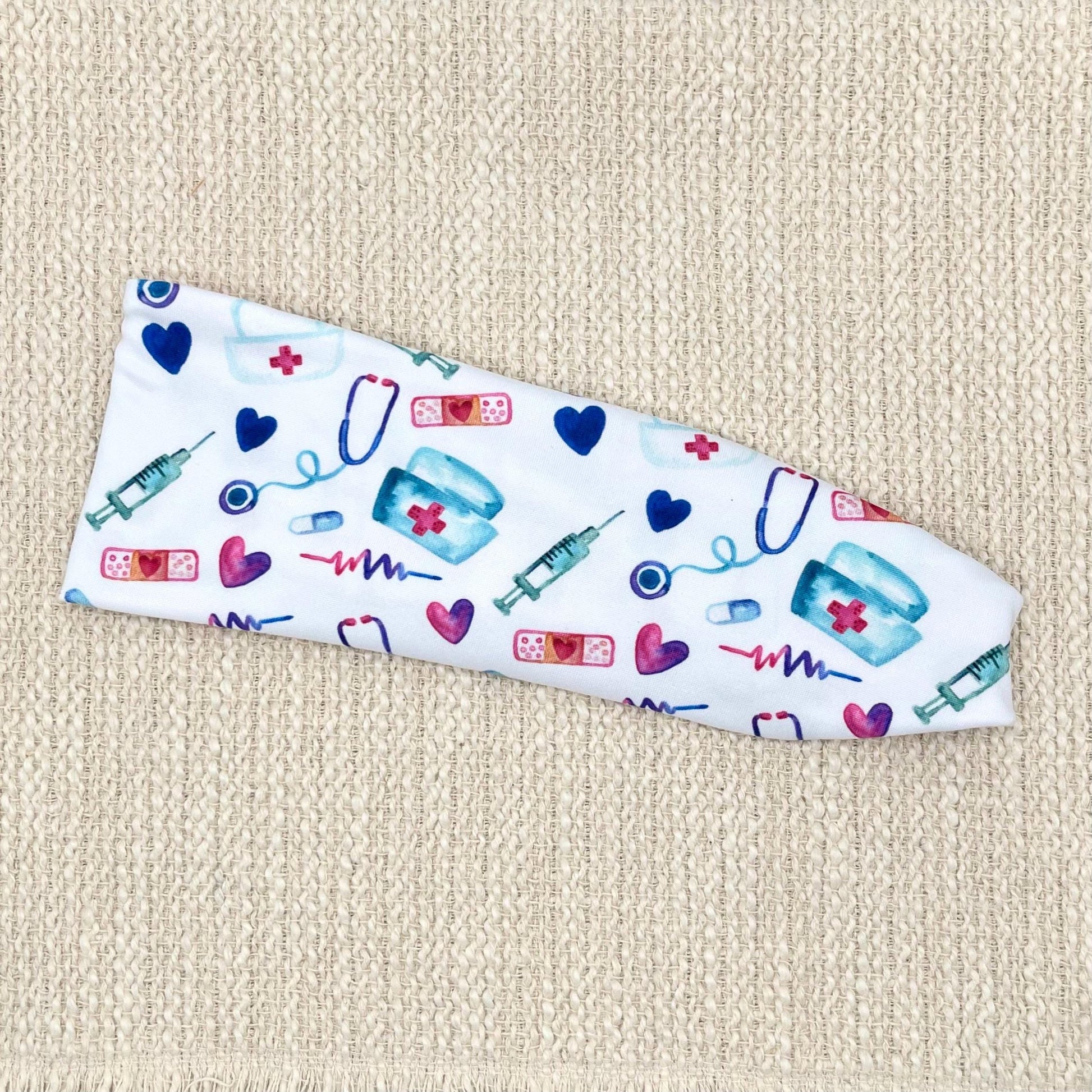 Flat, stretchy, white headband with pink, blue, and purple medical theme print.