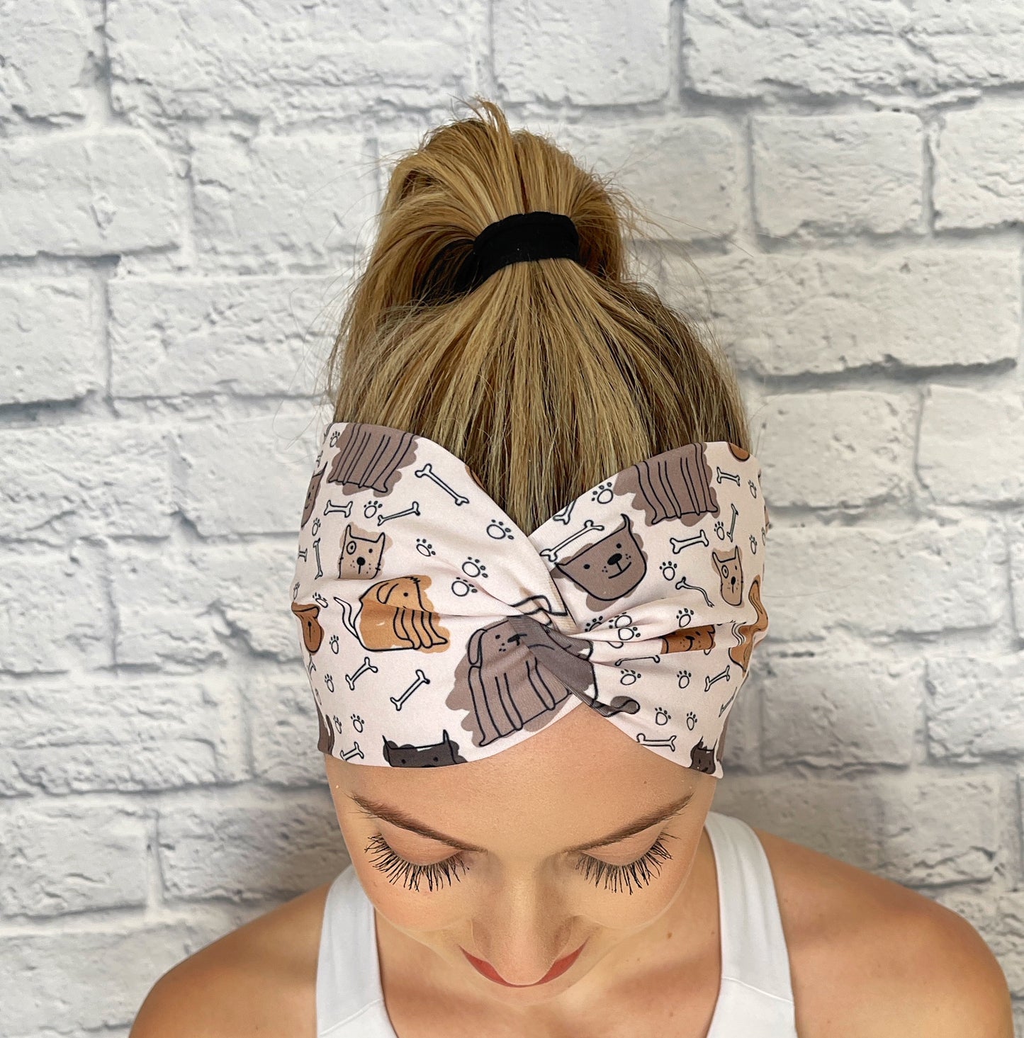 Woman with hair in ponytail wearing wide, twisted headband in brown with dog print.