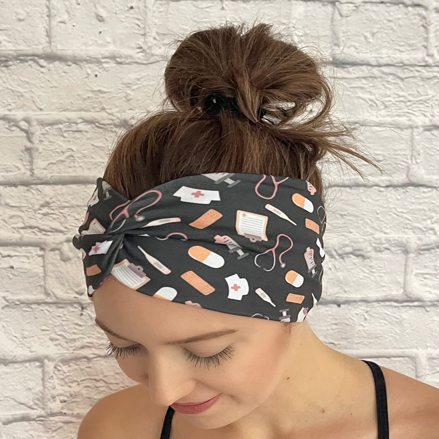 Woman wearing gray, wide twisted headband with medical theme print.