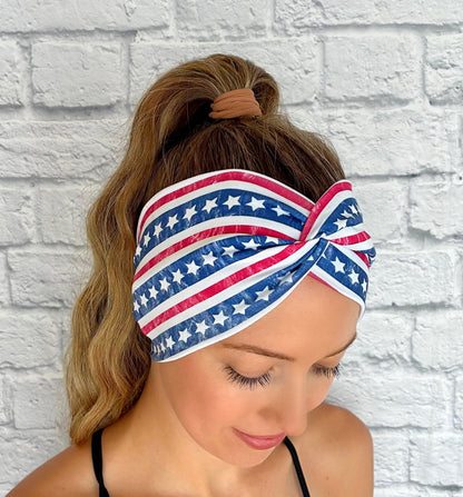 Woman with hair in ponytail wearing white wide twist headband with American Flag theme print.