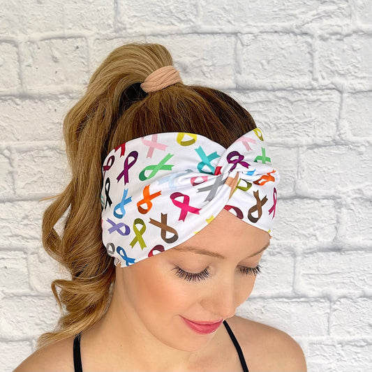 Woman with hair in curled ponytail wearing wide, twisted headband in white with varying color ribbon print.