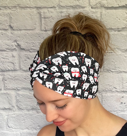 Woman with hair in bun wearing wide, twisted headband in black with white teeth print.