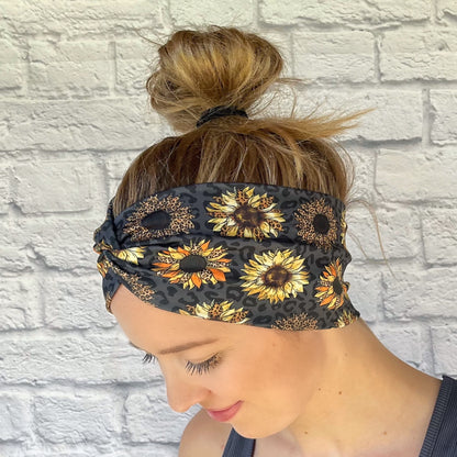 Woman with hair in bun wearing black, wide twisted headband with leopard print and sunflowers.