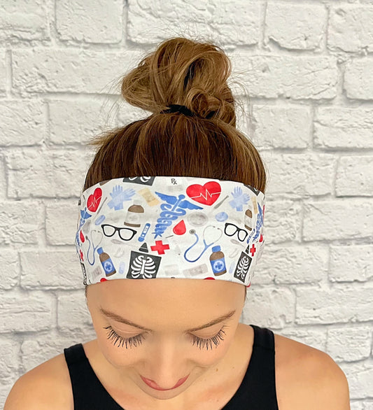 Woman with hair in bun wearing stretchy headband in light blue, red, and black medical theme print.