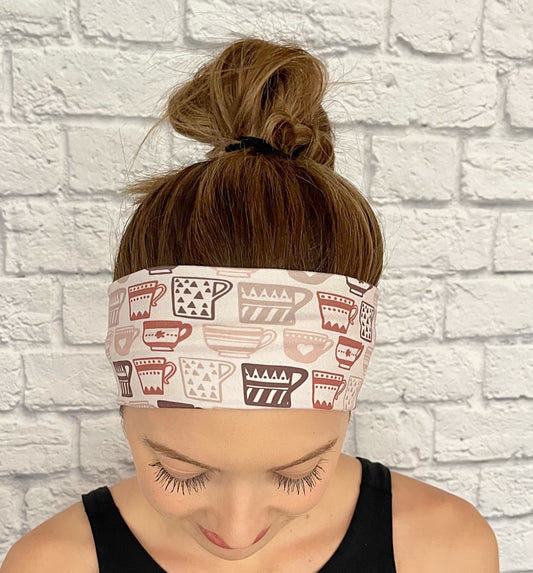 Woman with hair in bun wearing stretchy, light brown headband with brown coffee cup print.