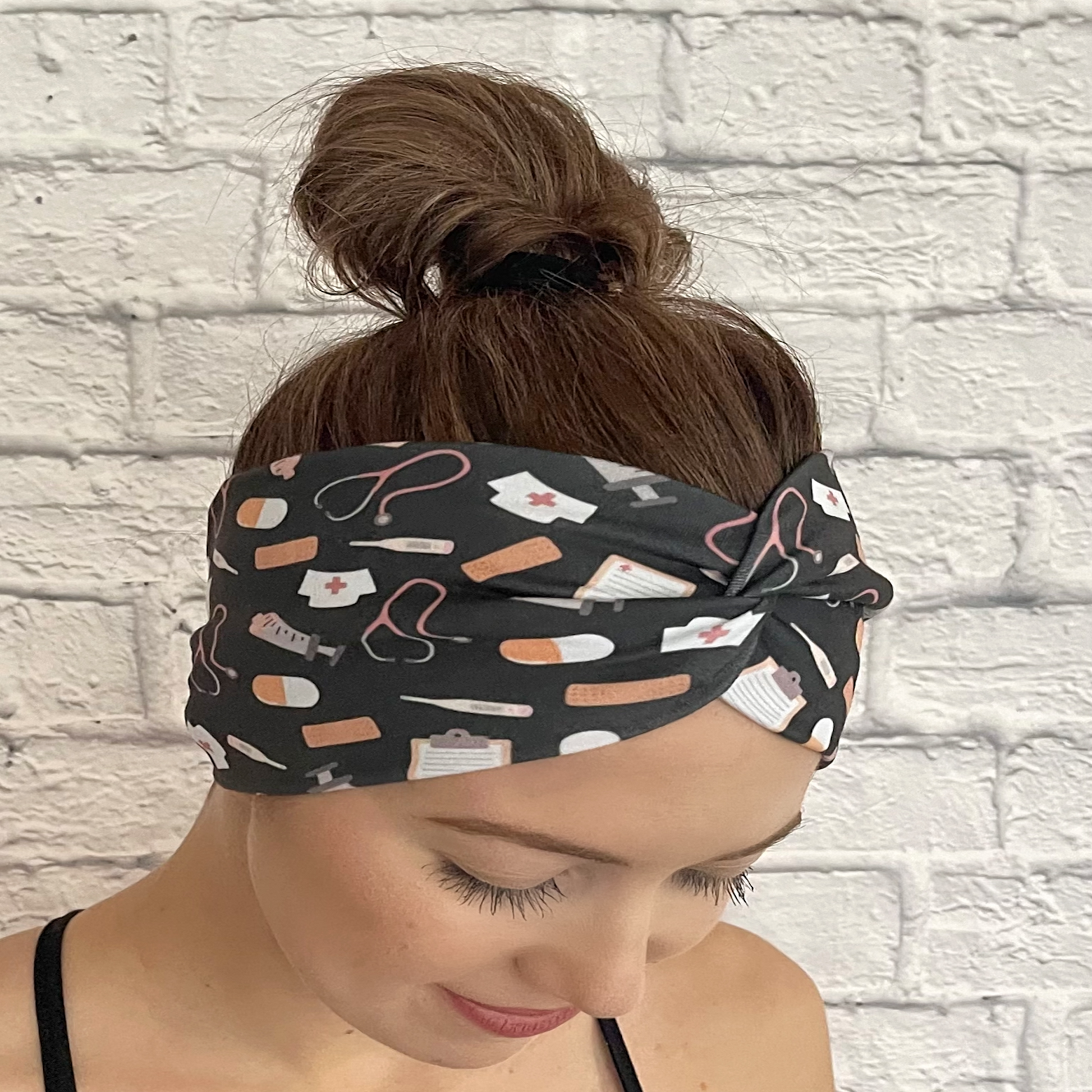 Woman wearing gray, wide twisted headband with medical theme print.