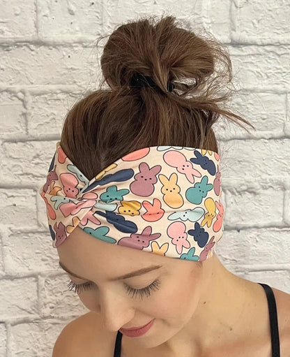 Woman with hair in bun wearing wide, twisted headband in peach/cream color with pastel print Easter bunnies.