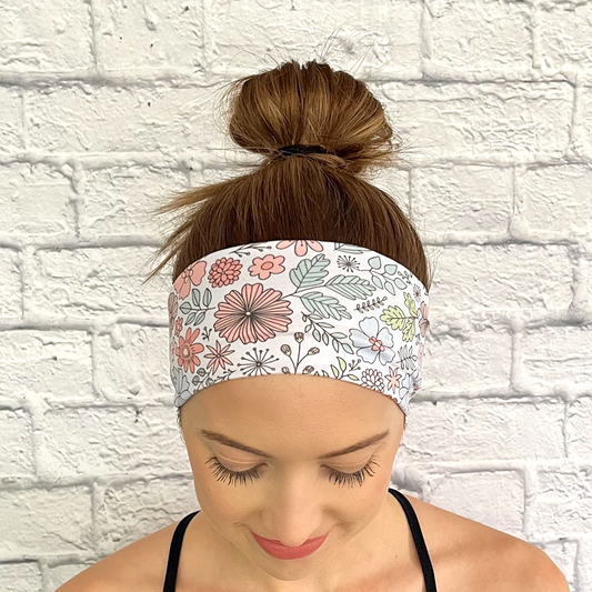 Woman with hair in bun wearing headband in white with pastel floral print.