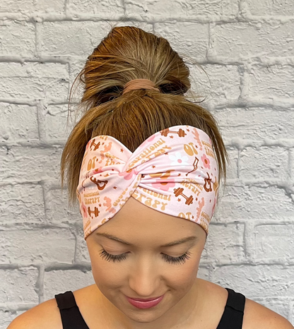 Woman with hair in bun wearing wide, twisted, pink headband with print- OT, occupational therapy with flowers, crutches, a wheelchair, and weights. 