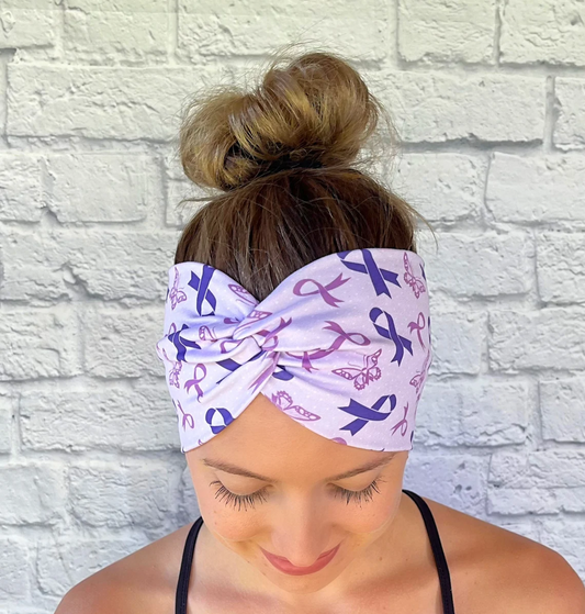 Woman with hair in bun wearing wide, twisted headband in light purple color with purple ribbon and butterfly print.