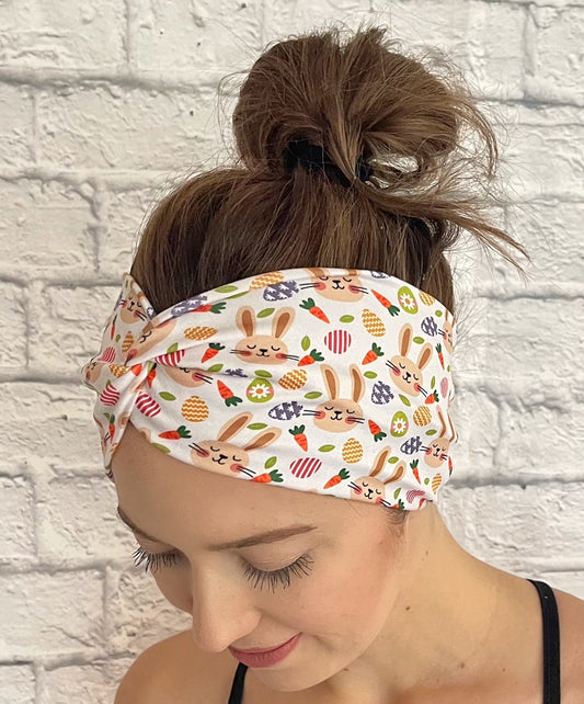 Woman with hair in bun wearing wide, twisted headband in light tan with Easter bunny theme print.