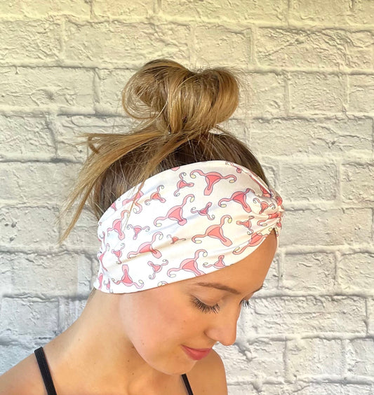 Woman with hair in bun wearing cream color, wide twist headband with uterus print.