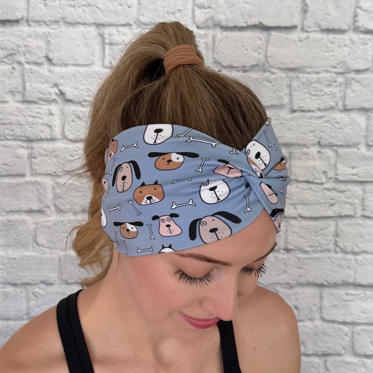 Woman with hair in ponytail wearing wide, twisted headband in blue with dog print.