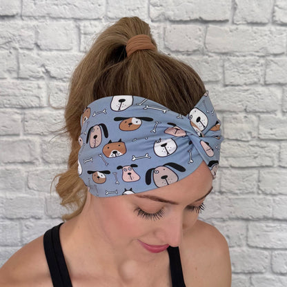 Woman with hair in ponytail wearing wide, twisted headband in blue with dog print.