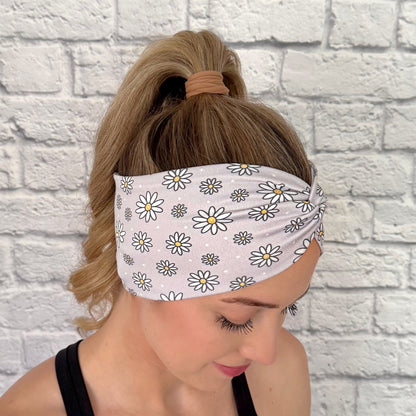 Woman with hair in ponytail wearing wide, twisted headband in gray with white daisy print.