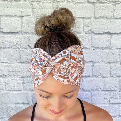 Woman wearing a fall theme, pumpkin spice patterned headband against a white brick wall
