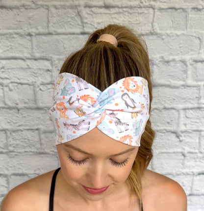 Woman with hair in ponytail wearing wide, twisted headband in white with baby animal and polka dot print.