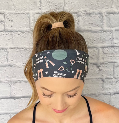 Woman with hair in curled ponytail wearing gray/black headband with print "physical therapy" and exercise/ therapy related items.