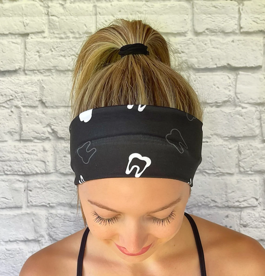 Woman with hair in ponytail wearing flat, stretchy, black headband with white teeth print.