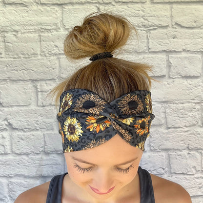 Woman with hair in bun wearing black, wide twisted headband with leopard print and sunflowers.