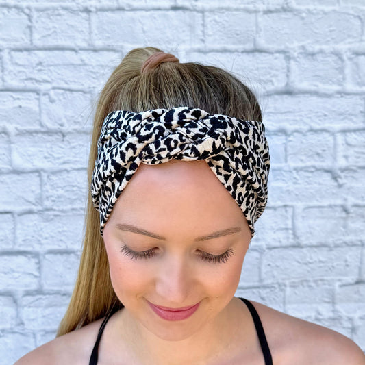 Woman with hair in ponytail wearing black and tan leopard print headband in sailor knot style with ribbed fabric.