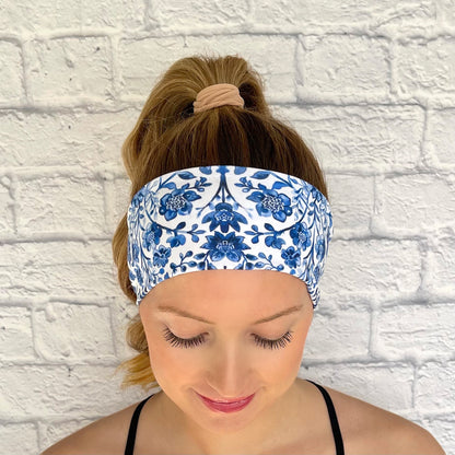 Woman with hair in curled ponytail wearing flat, stretchy, white headband with blue floral print.