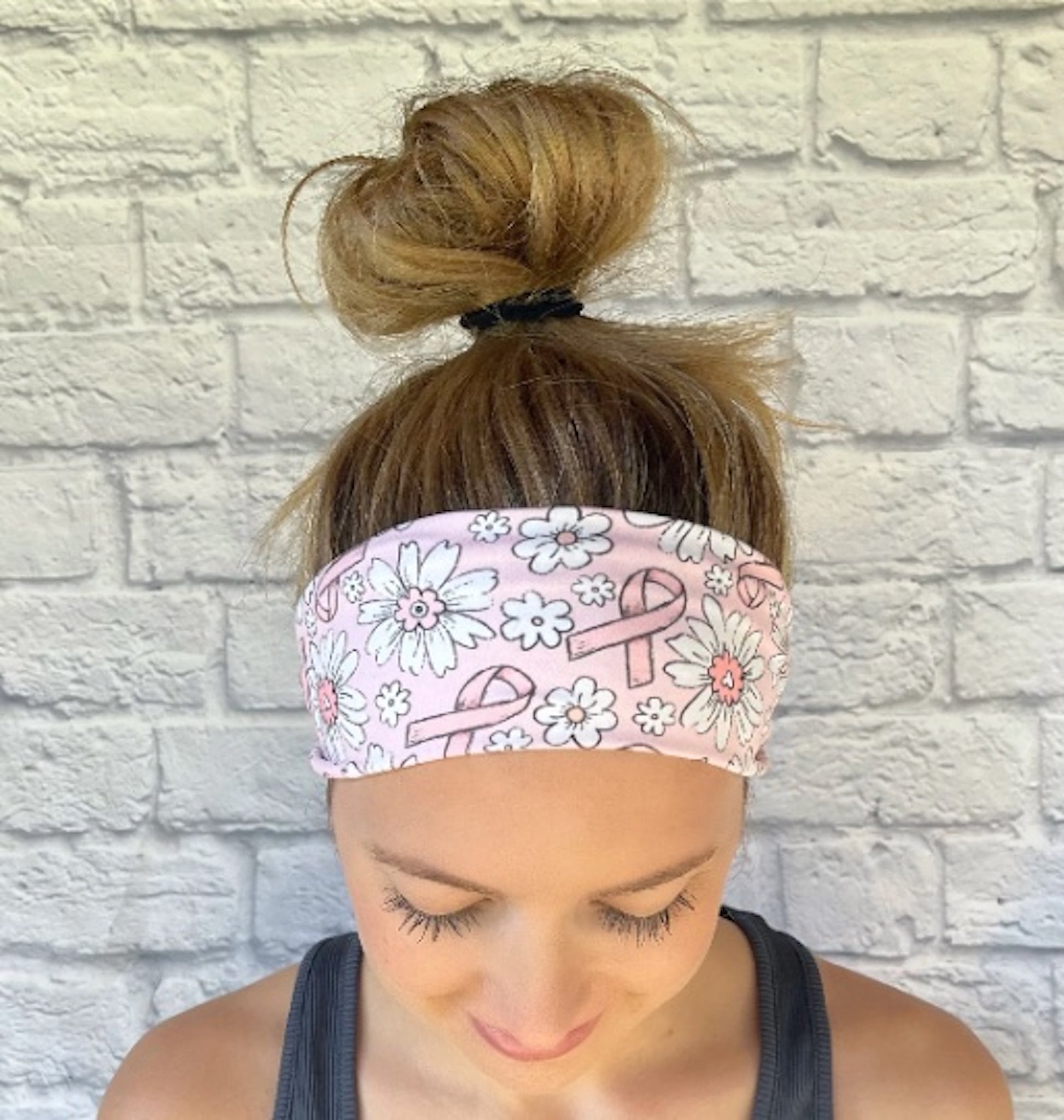 Woman wearing light pink headband with pink ribbons and white flowers.