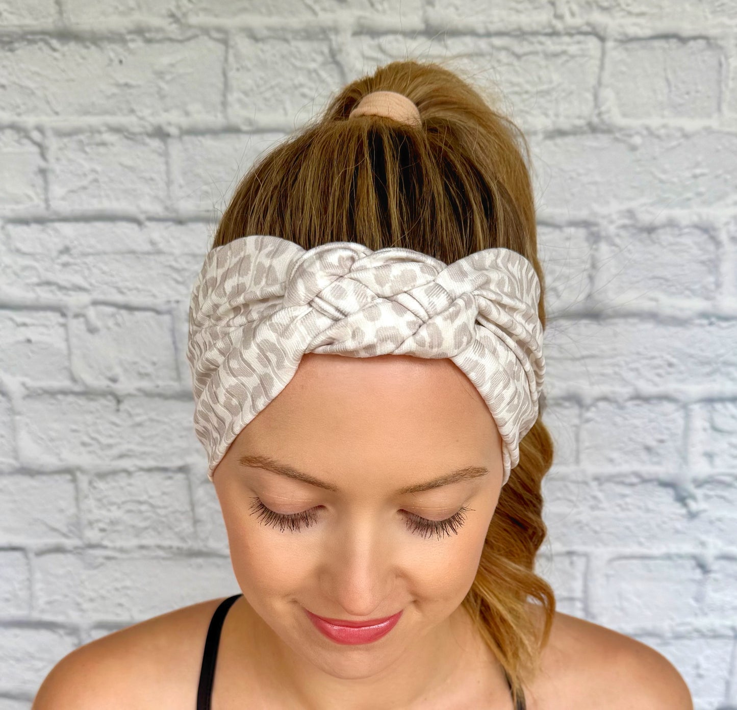 Woman with hair in ponytail wearing tan and white cheetah print headband in sailor knot style with ribbed fabric.
