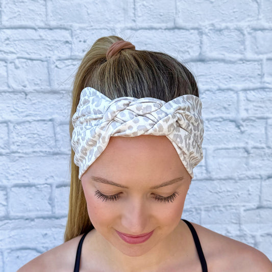 Woman with hair in ponytail wearing tan and white cheetah print headband in sailor knot style with ribbed fabric.