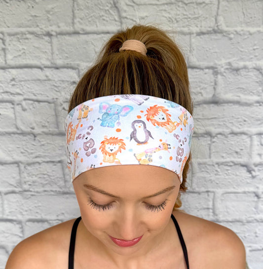 Woman with hair in ponytail wearing flat, stretchy headband in white with baby animal and polka dot print.