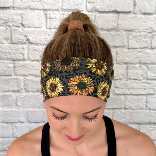 Woman with hair in bun wearing stretchy, black headband with sunflower and leopard print.