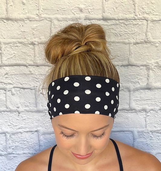 Woman with hair in bun wearing flat, stretchy, black headband with white polka dot print.