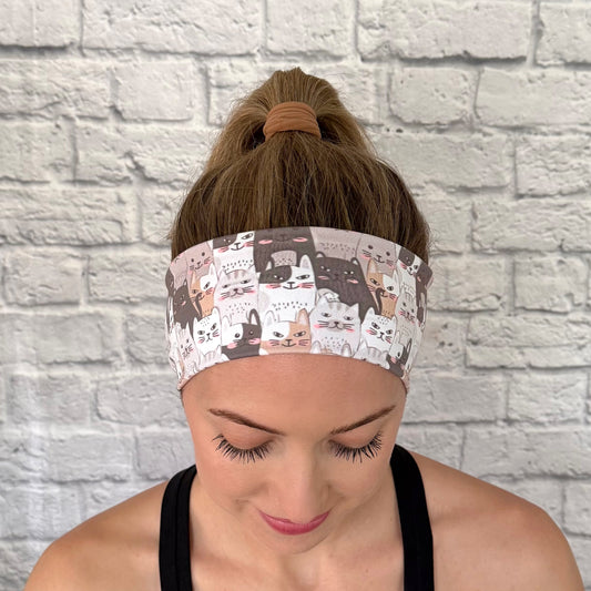 Woman with hair in bun wearing flat, stretchy headband with gray and tan cat print.