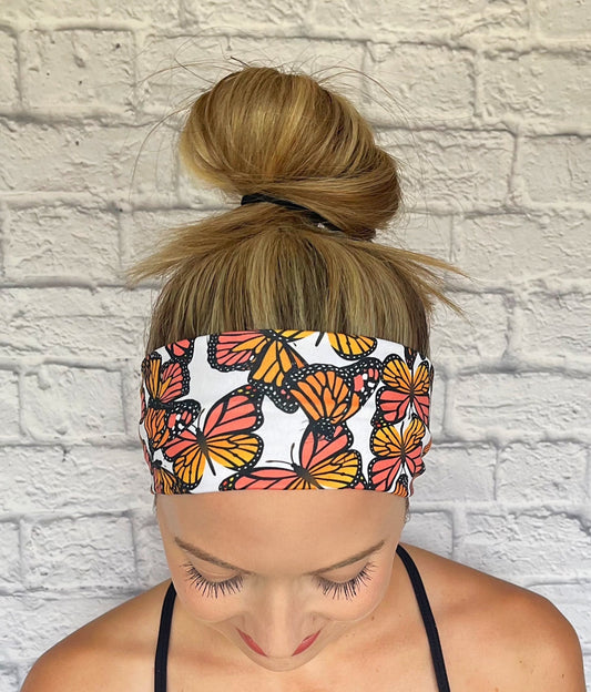 Person wearing a headband with butterfly pattern against a white brick wall.