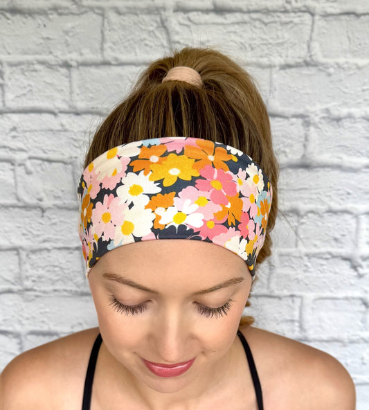 Woman with hair in ponytail wearing headband with light and dark pink, navy, light blue, white, yellow, and orange flower print.