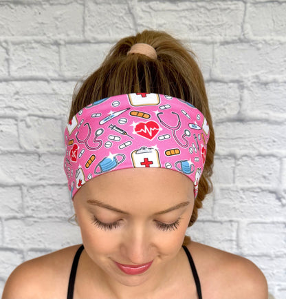 Woman with hair in ponytail wearing flat, stretchy, pink headband with medical theme print.