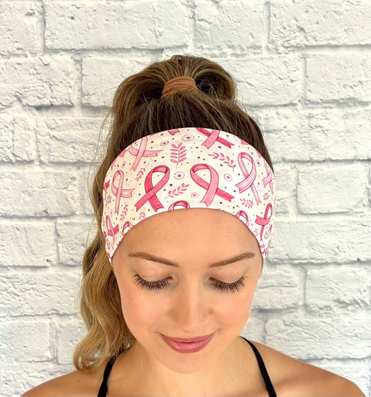 Woman with hair in ponytail wearing flat, stretchy headband with pink ribbon, leaf, and polka dot print.