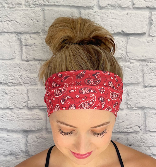 Woman with hair in bun wearing flat, stretchy red bandana print headband.