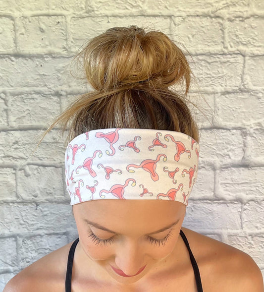 Woman with hair in bun wearing flat, stretchy, white headband with uterus print.