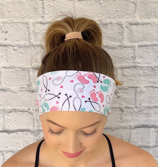Person wearing a headband with medical-NICU theme headband against a white brick wall.