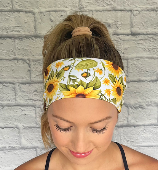 Woman with hair in ponytail wearing white stretchy headband with sunflower print.