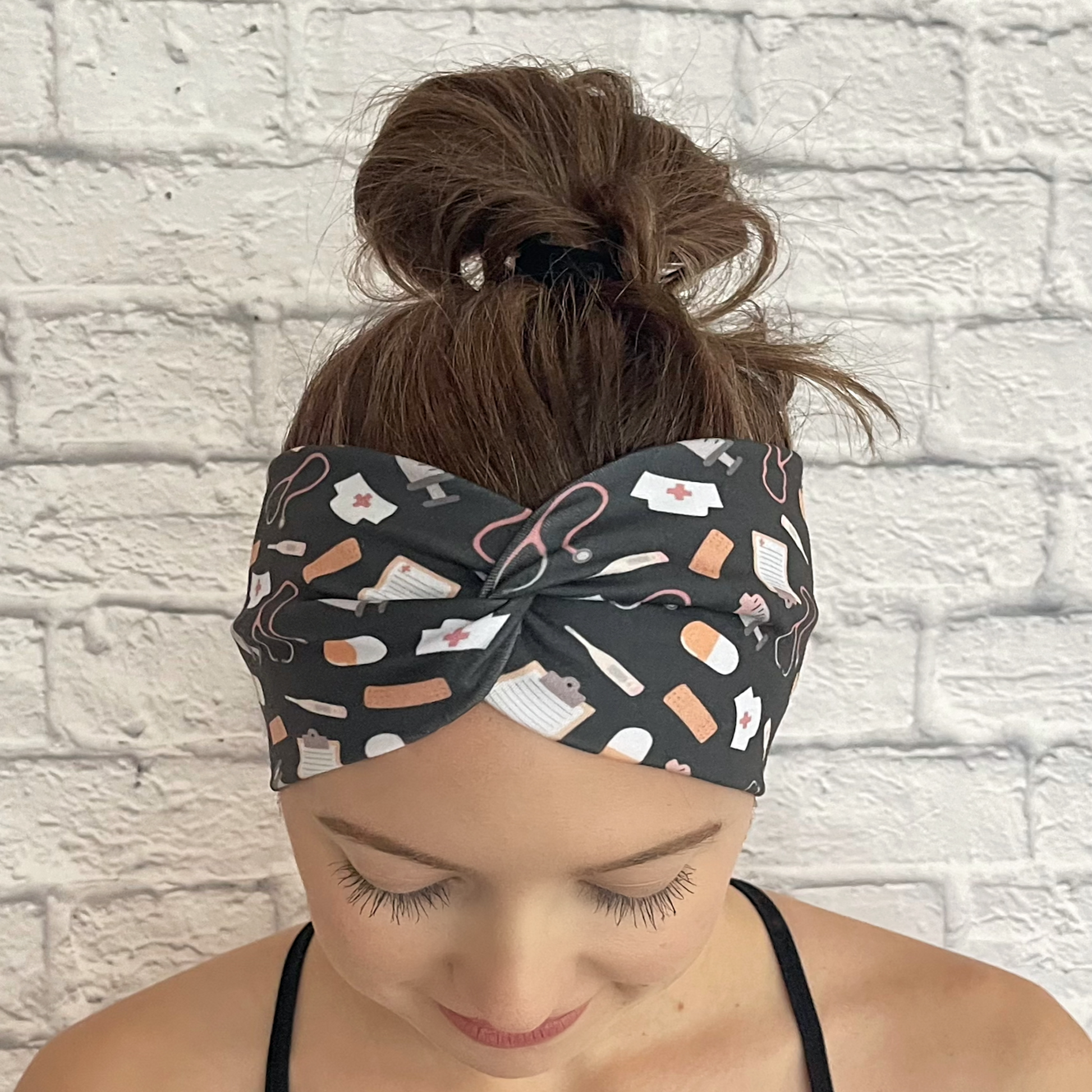 Woman wearing gray, wide twisted headband with medical theme print.