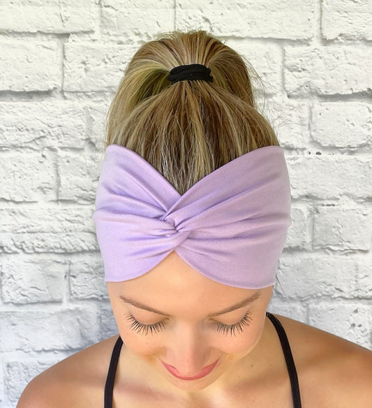 Woman with hair in ponytail wearing wide, twisted headband in lavender color.