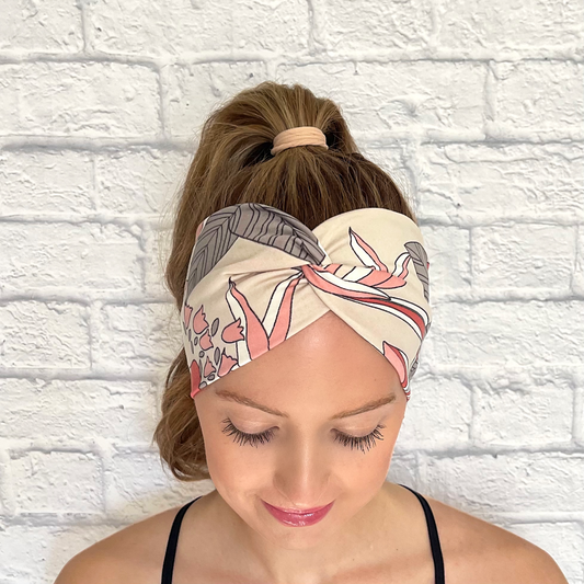 Woman with hair in curled ponytail wearing mauve, pink, gray, and white floral headband in wide, twisted style.