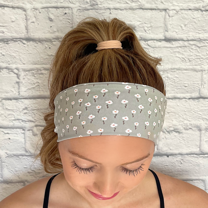 Woman wearing hair in ponytail with mint color headband with small white flowers.