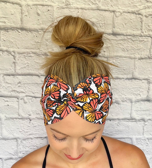 Woman with hair in bun wearing wide, twisted headband in white with monarch butterfly print.